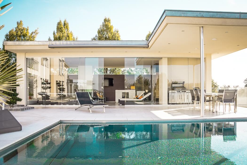 Fliessender Übergang vom Pool zum Haus mit überdachten Sitzbereich