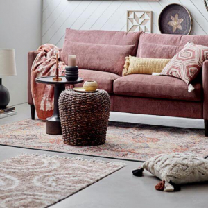 Bloomingville Teppich in Rosa-Tönen vor einem Sofa liegend