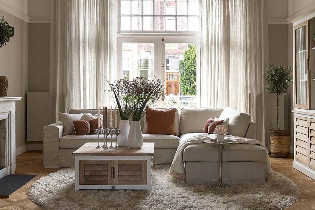Riviera Maison Sofa mit Pacifica Schränken in einem hellem Wohnzimmer mit flauschigem Teppich